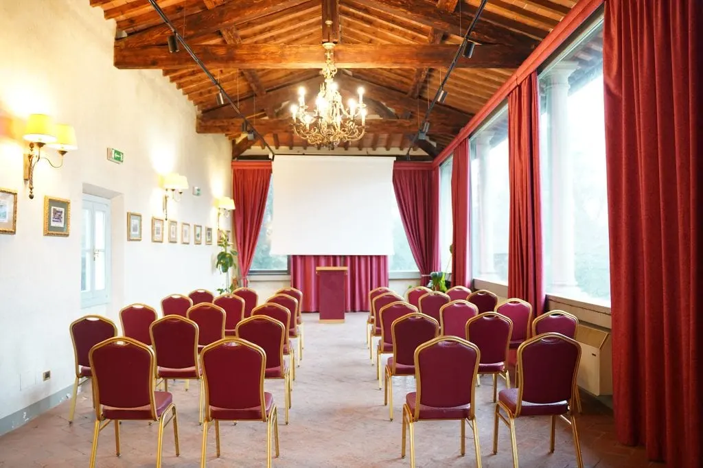 La sala meeting con le sedie in fila, le tende rosse e le travi a vista
