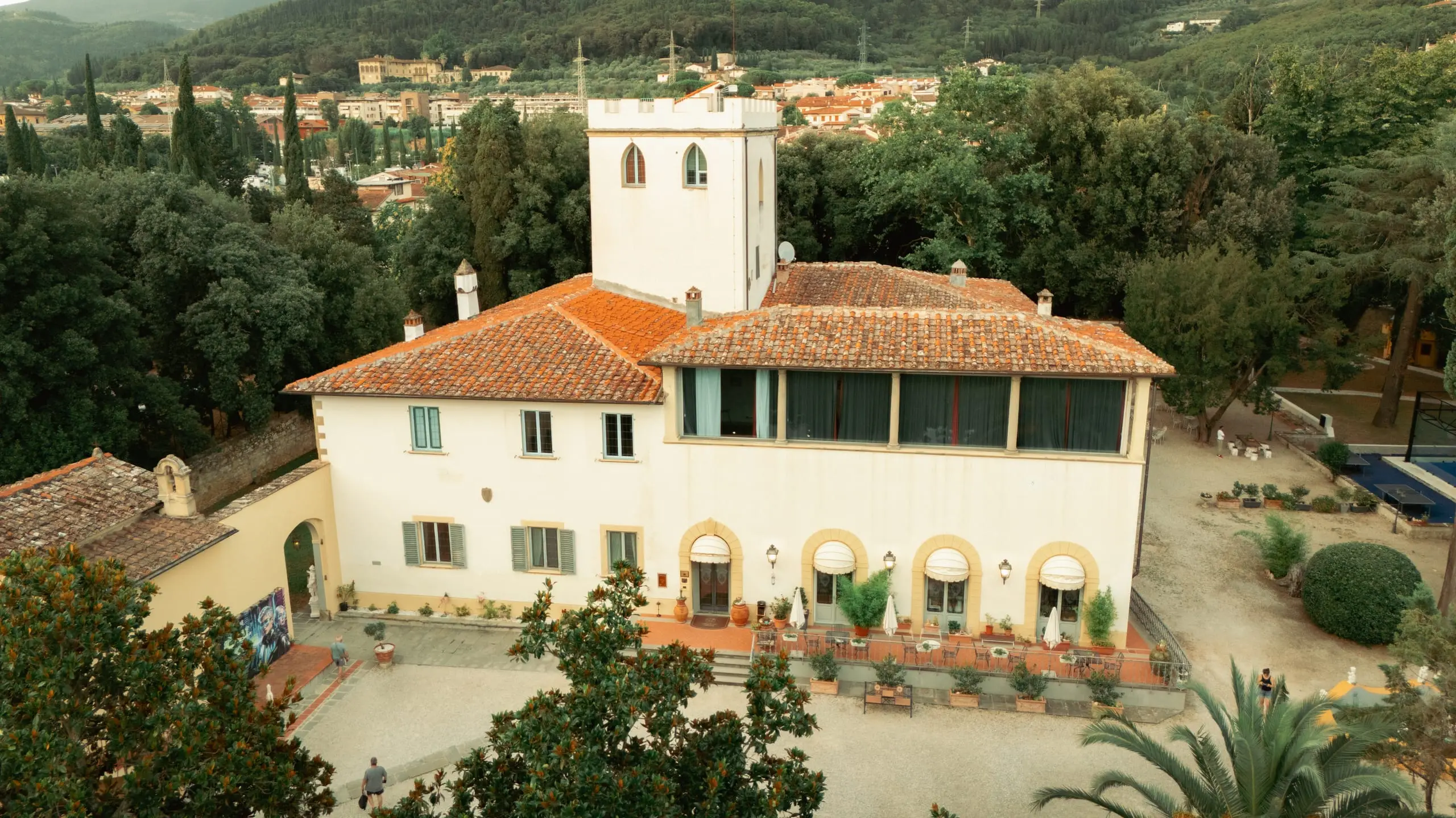 La villa vista dall'alto: i tetti in cotto, la torre e la loggia, con il parco intorno e la piana di Firenze sullo sfondo